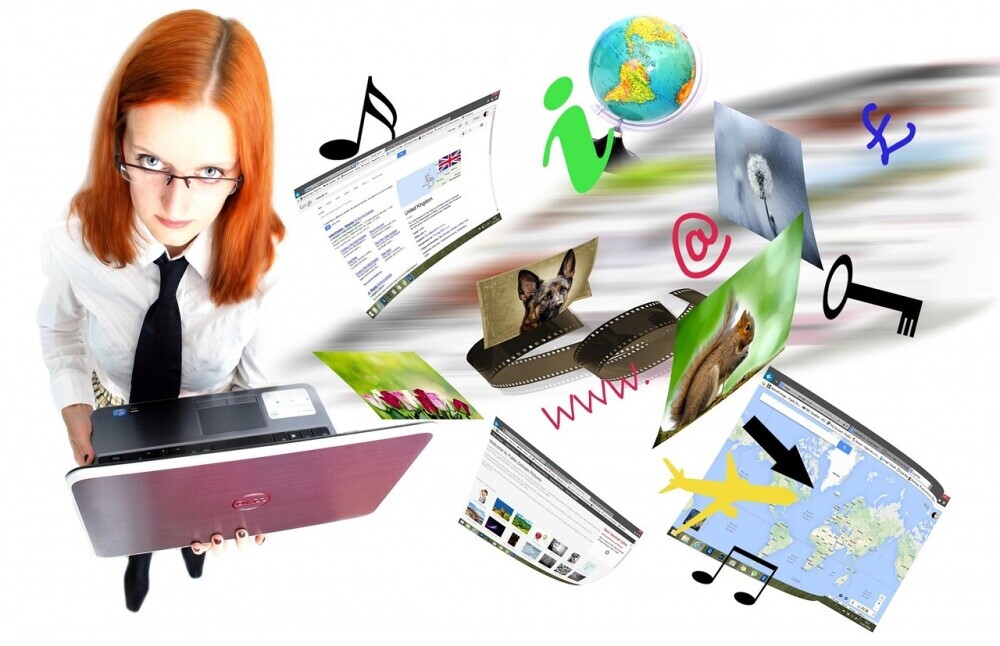 Woman with ginger hair in a suit holding a laptop with diffrent images floating next to her depicting different websites